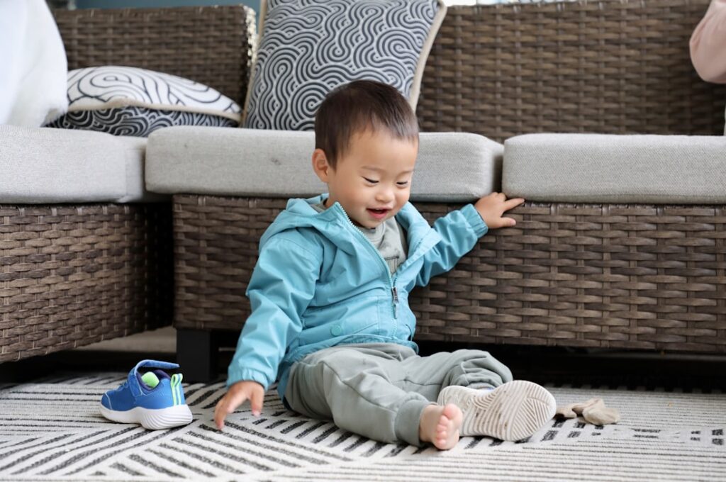 Tout-petit assis sur un tapis qui enlève ses chaussures tout seul